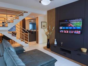 a living room with a couch and a staircase with a tv at House in Yolanda Village in Foz do Iguaçu