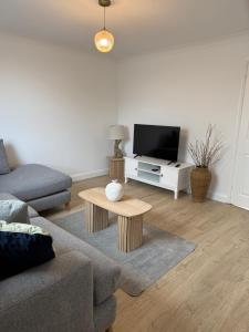a living room with a couch and a tv at Silver stays, calm coastal stay , close to beach in Gorleston-on-Sea