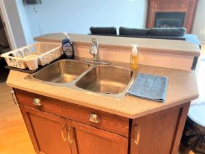a stainless steel sink in a kitchen with a couch at Spacious Duplex in Camrose +50 photos