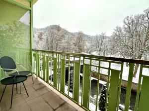 a balcony with a table and chairs and snow covered trees at Slunecni Lazne Apartments in Karlovy Vary
