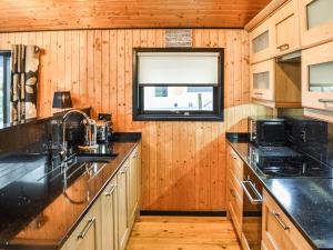a kitchen with wooden walls and counters and a window at Glendowlin Lodge Retreat in Tirril +9 photos