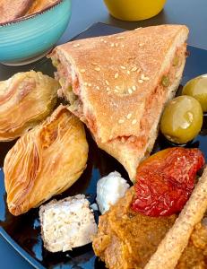 a plate of food with bread and pastries and olives at Follow the Sun Boutique Hostel - Pool, Breakfast & Sea Views in St. Julianʼs