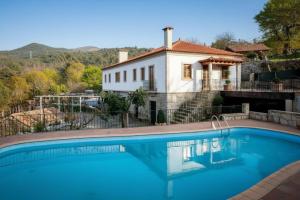 a house with a swimming pool in front of a house at Cerca dos Passais in Entre Ambos os Rios