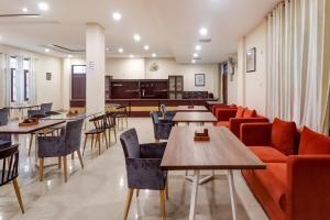 a living room with tables and chairs and a couch at Capital O Divira Inn in Dhanbād +47 photos