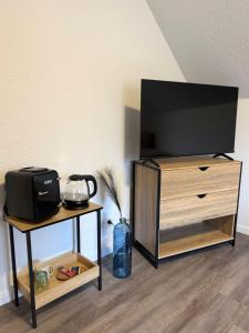 a flat screen tv on a wooden stand with a table at emsRoom - Gästezimmer in Düne