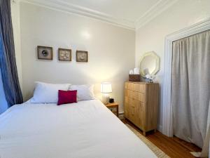 a bedroom with a white bed with a red pillow at Cozy 1Bed, 1Bath in Brookline, MBTA in Brookline +2 photos