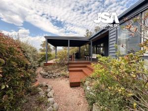 a house with a porch with a wooden deck at Kalkite Cottage in Kalkite