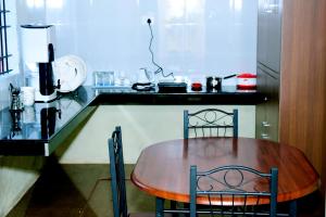 uma cozinha com uma mesa de madeira e 2 cadeiras em Holidayincoorg Cozy Nest em Madikeri