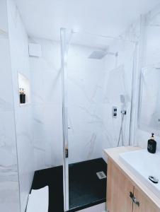 a white bathroom with a shower and a sink at Ocean Bleu Toulouse in Toulouse