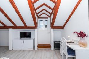 a dining room with a table and a tv in a attic at Rooms Bed and Breakfast Blanc in Pučišća