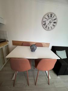 a white table with two chairs and a clock on the wall at La Luna - Danny in Heerhugowaard +16 photos