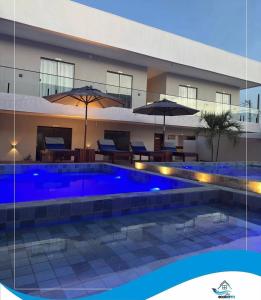 a swimming pool in front of a building with umbrellas at Condomínio Vila Eco Barra apto 215 in Barra Grande