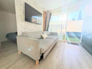 a living room with a couch and a tv at Suite Évasion Spa - Tiny House in Vernouillet