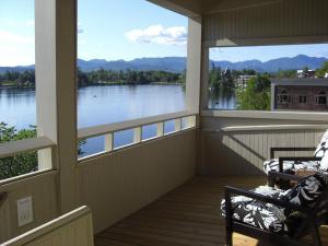 a screened porch with two chairs and a view of a lake at The Haus on Mirror Lake in Lake Placid