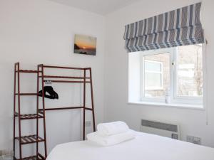 a white bedroom with a bed and a window at Gilly's Cottage in Kingsbridge