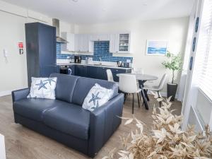 a living room with a blue couch and a kitchen at Vista Mare 2 in Weymouth