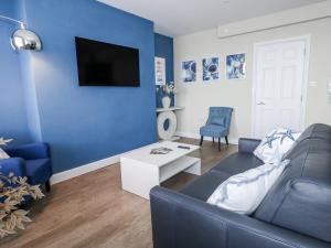 a blue living room with a couch and a tv at Vista Mare 2 in Weymouth
