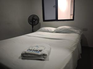 a bed with two towels on it with a fan at Denier House Guabinal - Cerca de Centros Comerciales in Ibagué