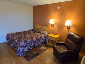 a hotel room with a bed and a chair at Travelers Lodge Marshall in Marshall