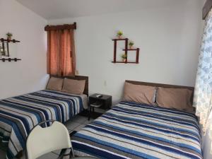 a bedroom with two beds and a chair in it at Cómoda habitación Mar in Veracruz +4 photos