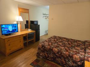 a hotel room with a bed and a desk with a television at Travelers Lodge Marshall in Marshall