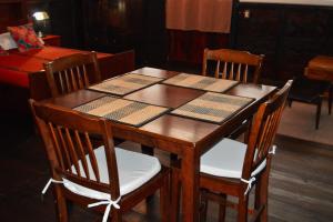 a wooden table with four chairs and a table with books on it at El Refugio - Hospedaje y Eventos in San Lucas Sacatepéquez