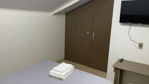 a room with a bed with a tv and towels at Estadia Do Vale Hospedaria União da Vitória in União da Vitória +24 photos