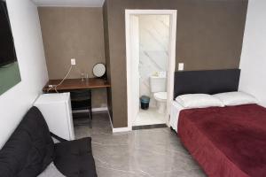 a bedroom with a bed and a desk and a bathroom at Apartamento com Custo Benefício Imbatível in Passo Fundo