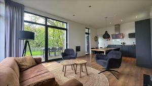 a living room with a couch and chairs and a table at Bad Hoophuizen Chalet L-Cube 6 Nr Eik 19 in Hulshorst