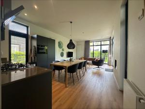 a kitchen and living room with a table and chairs at Bad Hoophuizen Chalet L-Cube 6 Nr Eik 19 in Hulshorst +19 photos