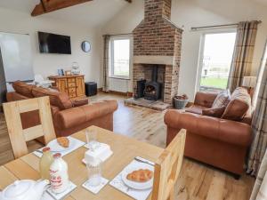 a living room with a table and a fireplace at Grey Croft in Embleton