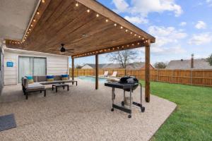 a patio with a grill and a wooden pergola at DFW Retreat - Pool, Spa & Minutes to Dallas & Fort Worth in Flower Mound