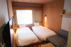 a small room with two beds and a window at Lake Side Inn MIRAHAKONE in Hakone