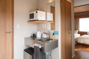 a small kitchen with a sink and a microwave at Lake Side Inn MIRAHAKONE in Hakone