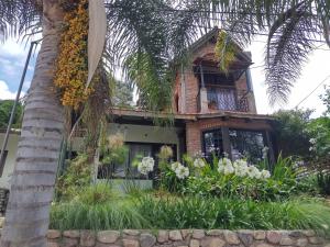 a house with a palm tree in front of it at Casa laberinto, Entre cerros, cómoda cama de 2x2 in Salta