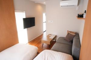a small living room with a couch and a tv at Lake Side Inn MIRAHAKONE in Hakone
