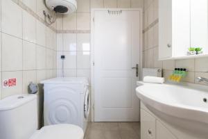 a white bathroom with a toilet and a sink at Casa Carina in Lakíthra