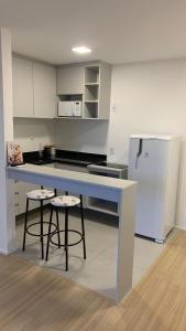 a kitchen with a counter with two stools and a refrigerator at SeuLoft 110SouMais in Niterói
