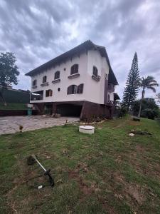 a large white house with a grass field in front of it at Caminho das Pedras 206 in São Pedro da Aldeia