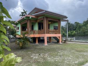 a small green house with a deck on a yard at Srisook House in Ko Phangan