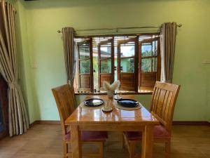 a dining room with a wooden table and a window at Srisook House in Ko Phangan