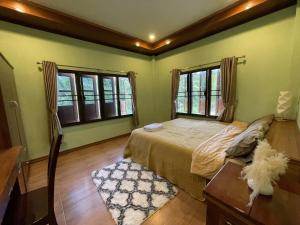 a bedroom with a bed and two windows at Srisook House in Ko Phangan