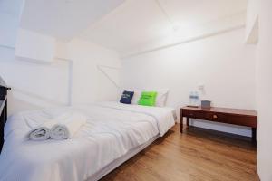 a white bedroom with a bed and a desk at Urbanview TeBeYe Syariah UNS Solo in Solo