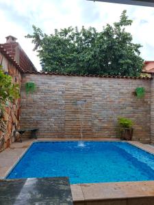 a swimming pool in a brick wall with a water fountain at Cantinho Abençoado in Pirenópolis
