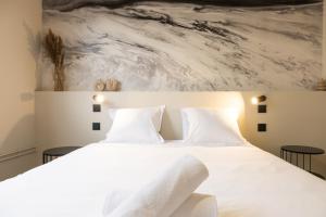 a bedroom with a white bed with a painting on the wall at Le Rhône - Aux Charmes Lyonnais ' in Lyon