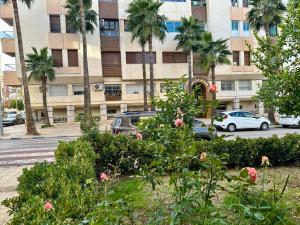 a building with palm trees and cars parked in front at Jawhara Jacobs apartment in Fez