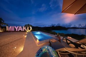 a swimming pool at night next to a body of water at クリスタルヴィラ大浦 in Miyako-jima