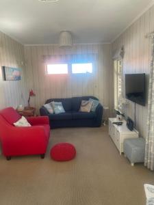 a living room with a blue couch and a red chair at Bosuns Locker in Auckland