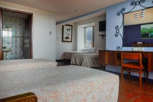 a hotel room with two beds and a desk at Hotel Savoy Inn in Quito