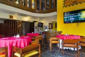 a dining room with red tables and chairs and a tv at Hotel Savoy Inn in Quito